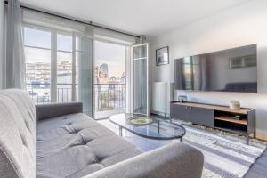 een woonkamer met een bank en een tv bij Appartement neuf, lumineux & cosy proche La Défense, Neuilly & Paris in Puteaux