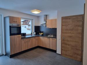 eine Küche mit Holzschränken, einem Fenster und einer Tür in der Unterkunft Apart Madeleine in Sankt Leonhard im Pitztal