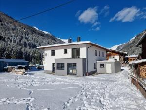 ein weißes Haus im Schnee mit Bergen im Hintergrund in der Unterkunft Apart Madeleine in Sankt Leonhard im Pitztal