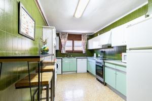 eine Küche mit grünen Wänden und weißen Schränken in der Unterkunft Apartament el Llac in Puigcerdà