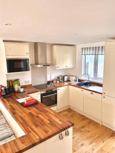 a kitchen with white cabinets and a wooden counter top at Nola Lodge in Cirencester
