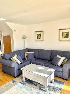 a living room with a blue couch and a coffee table at Nola Lodge in Cirencester