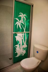 a bathroom with a toilet and a green wall with palm trees at Coliving La Rebeca Pereira in Pereira