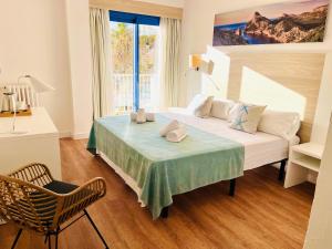 a bedroom with a bed and a chair and a window at Hotel Miramar in Port de Soller