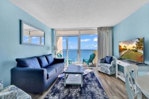 a living room with a blue couch and a tv at Bay Watch Resort 1203 - Perfect Oceanside Getaway in Myrtle Beach