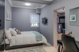 a bedroom with a bed and a desk and a chair at Trendy Cottage Hideaway in Cape Town