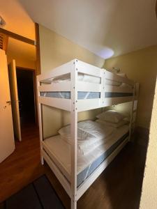 2 białe łóżka piętrowe w pokoju z korytarzem w obiekcie Studio 941-Particulier-Résidence L'Ours Blanc-Alpe d'Huez-Centre Station w LʼAlpe-dʼHuez
