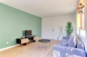 een woonkamer met een blauwe bank en een tv bij Le Petit Nid - Montigny in Montigny-le-Bretonneux