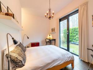 een slaapkamer met een bed en een groot raam bij Cozy forest villa on the water near Harderwijk in Zeewolde