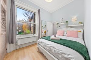 a bedroom with a bed and a large window at Artist's Bright Hampstead Heath Village 2 bed in London