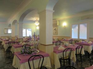 una habitación con mesas y sillas con manteles rosados en Hotel Maxim en Caorle