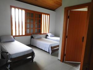 a bedroom with two beds and a window at Reserva Som das Águas in Caparaó Velho