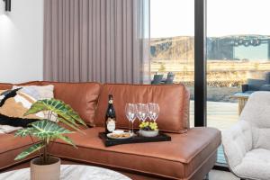 a living room with a brown leather couch with wine glasses at Luxury Villa in the South - Perfect Location in Ölfus