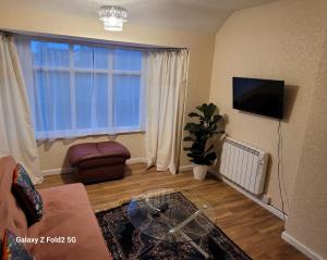 a living room with a couch and a tv and a window at Rest & Relax Apartment in Tilehurst