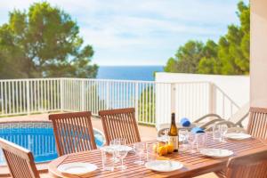 a wooden table with glasses and a bottle of wine at Villa Mirador B by Sonne Villas in Cala Galdana