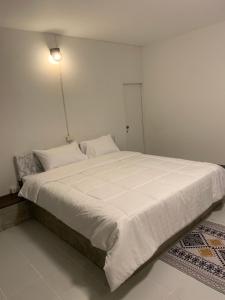 a large white bed in a white room with a light at Asny Home in Chiang Mai