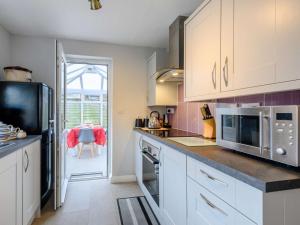 a kitchen with white cabinets and a microwave at 3 Bed in Sheringham 86262 in Sheringham