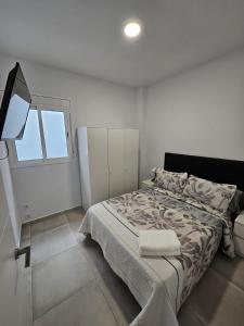 a white bedroom with a bed and a window at Apartamentos La Meridian in Barcelona