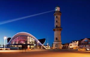 un phare à côté d'un bâtiment et d'un bâtiment dans l'établissement Ferienhaus Strandkoje, à Warnemünde