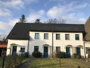 a white house with a black roof at Ferienhaus Waterkant in Warnemünde