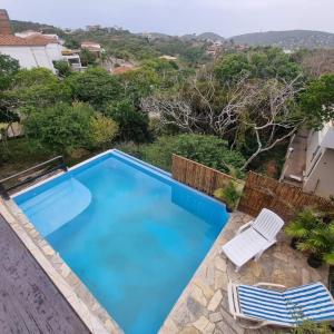 a large blue swimming pool with two white chairs at Villa Ferradura in Búzios