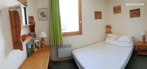 1 dormitorio con cama blanca y ventana en Appartement Les Sonnailles, en Les Allues