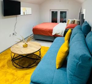 a living room with a blue couch and a bed at Studio apartman Cuprija in Cazin