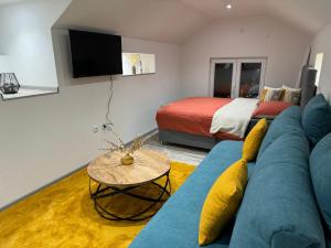 een woonkamer met een blauwe bank en een bed bij Studio apartman Cuprija in Cazin