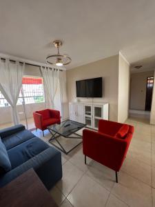 sala de estar con sofá azul y sillas rojas en Stylish Stay Ciudad Juan Bosch, en Los Paredones