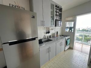 ブエノスアイレスにあるDepartamento luminoso y amueblado en caballitoのキッチン(ステンレス製の冷蔵庫付)、窓が備わります。