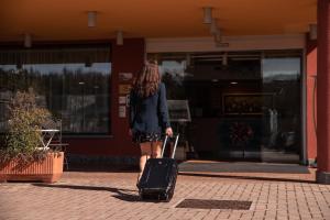 a woman pulling a suitcase in front of a store at Hotel Residence Montelago in Ternate