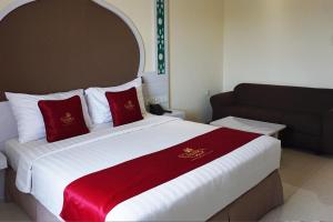 a hotel room with a large bed with red pillows at Namira Syariah Hotel Surabaya in Surabaya