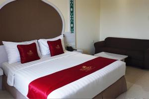 una habitación de hotel con una cama grande con almohadas rojas en Namira Syariah Hotel Surabaya, en Surabaya