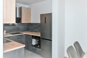 a kitchen with a stainless steel refrigerator and wooden cabinets at Špansko view -Comfy apartment in Zagreb