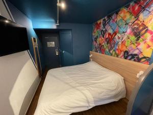 um pequeno quarto com uma cama e uma parede colorida em Egg Hôtel Sarcelles em Sarcelles