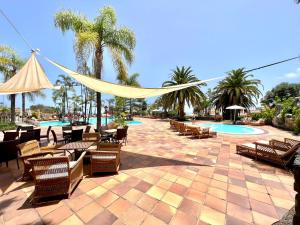 eine Terrasse mit Stühlen und einer Hängematte neben einem Pool in der Unterkunft Apartamento AP1 en Playa de Los Roques, en lado de la playa, con piscina in Los Realejos