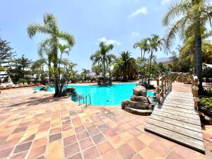 einen Pool in einem Resort mit Palmen in der Unterkunft Apartamento AP1 en Playa de Los Roques, en lado de la playa, con piscina in Los Realejos