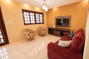 uma sala de estar com um sofá e uma televisão e cadeiras em Casa de campo c lazer completo e WiFi Bezerro PE em Bezerros