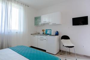 - une cuisine blanche avec un lit, un évier et une chaise dans l'établissement Studio apartment Stella, à Labin 6 autres photos