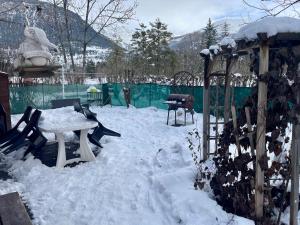um quintal coberto de neve com uma mesa e uma grelha em Chalet à proximité de l'Ubaye em Jausiers