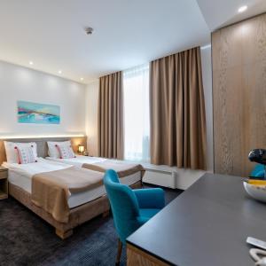 Habitación de hotel con cama y silla azul en Studio u Hotelu Alibi Inn, en Zlatibor