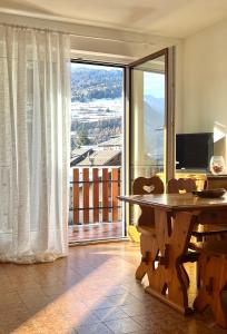 Zimmer mit einem Tisch und einem großen Fenster in der Unterkunft Gloria Holiday Home Bormio in Bormio