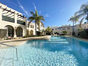 uma piscina em frente a um edifício com palmeiras em Las Casitas de la Playa em Vera