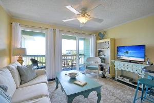 uma sala de estar com um sofá, uma televisão e uma mesa em 304A Sea Cabin em Isle of Palms