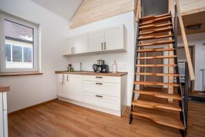 una cocina con armarios blancos y una escalera de madera en Ferienhaus Tiny Time, en Krumbach