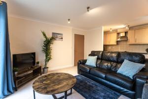 a living room with a leather couch and a table at April Disc - Long Stay - Contractors in Bristol