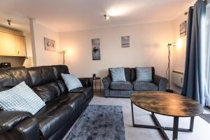 a living room with a leather couch and a table at April Disc - Long Stay - Contractors in Bristol