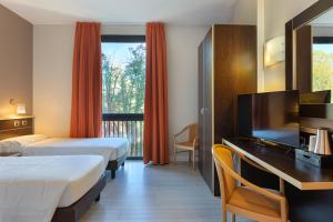 Cette chambre comprend deux lits et un bureau avec une télévision. dans l'établissement Hotel Ristorante Al Mulino, à Alexandrie