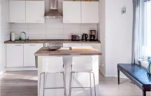 eine Küche mit weißen Schränken und einer Theke mit Stühlen in der Unterkunft Lovely Home In Wittstock With Kitchen in Wittstock
