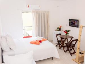 a bedroom with a bed and a table and a window at Residencial Santa Fé in Trancoso